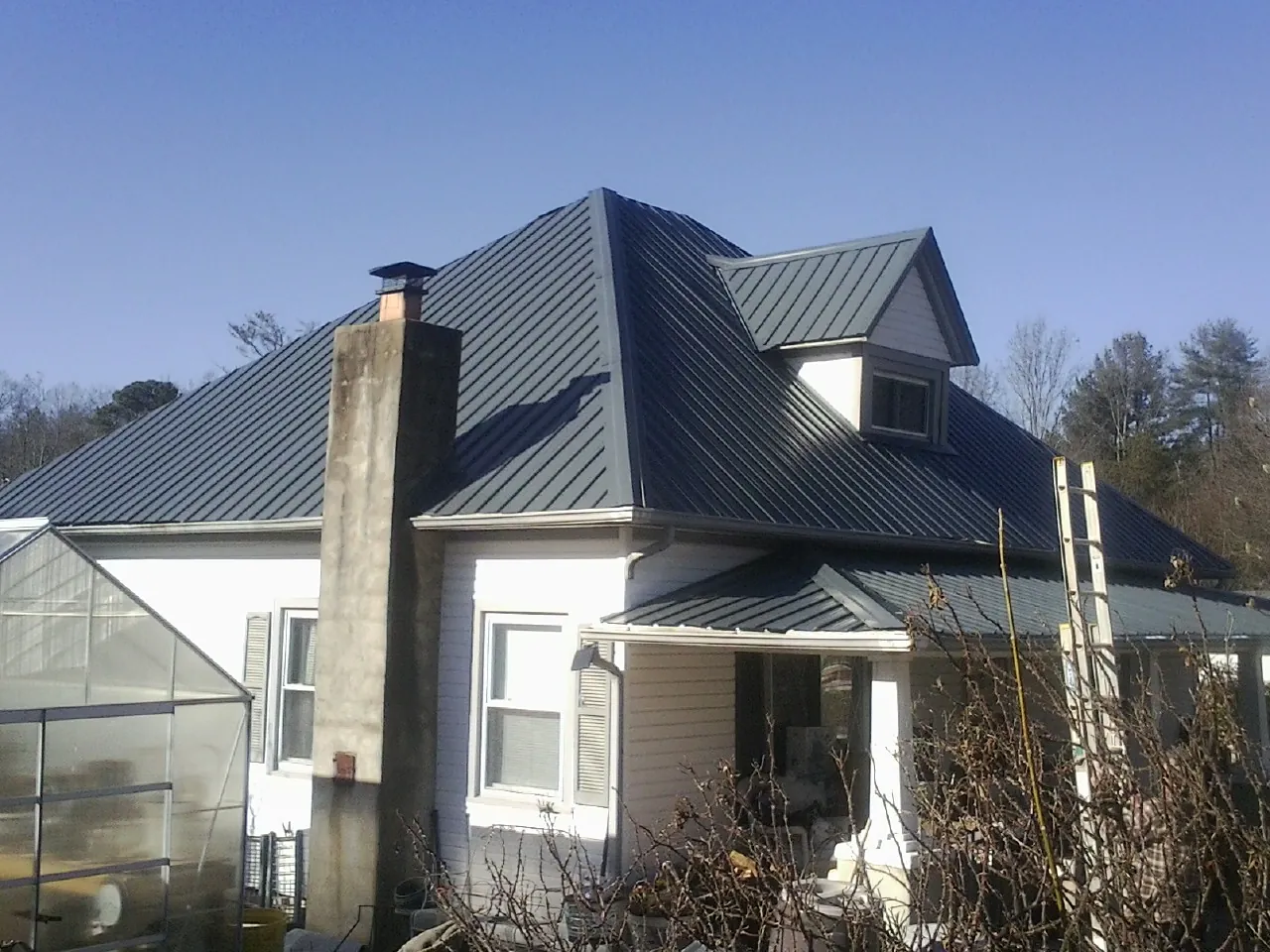 Dark blue standing seam metal roof on a white farmhouse with dormer — Slate & Tile Roof Repair by Roofing Brothers in Harcourt