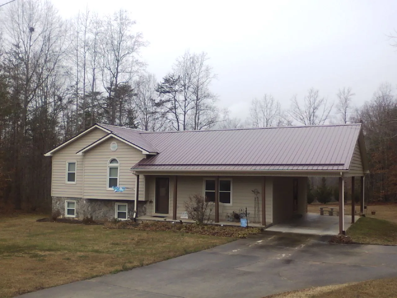 Burgundy metal roof on a tan split level home with an attached carport in Harcourt