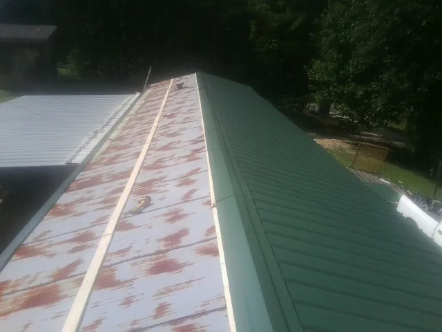Old rusted panels beside newly installed green metal roofing — Wind Damage Roof Repair by Roofing Brothers in Harcourt