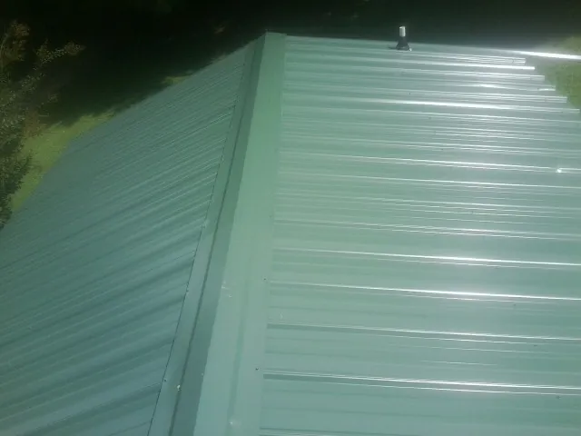 New green metal panels meeting at the ridge of a roof — Flat Roof Repair work by our crew in Harcourt