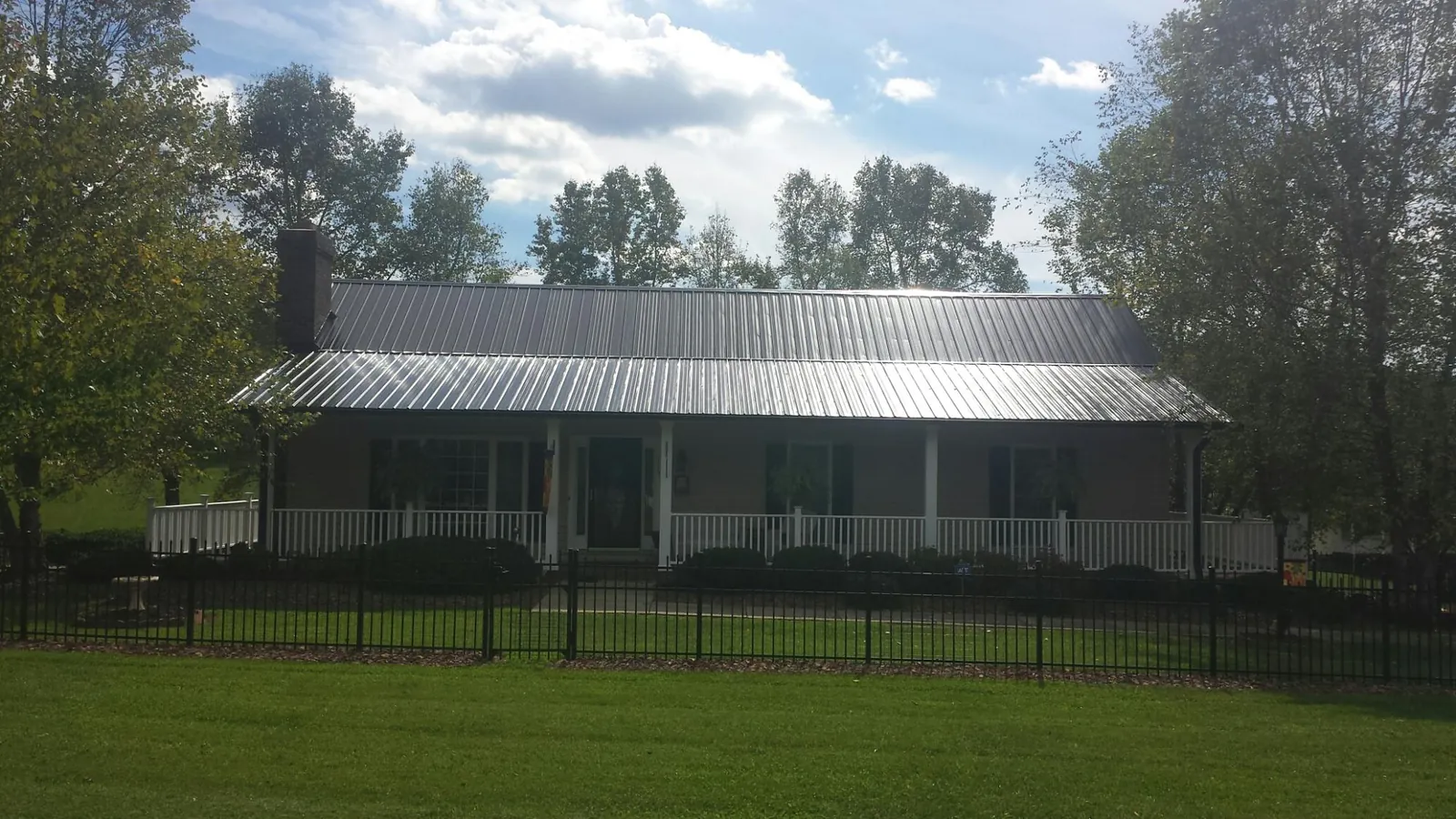 Gray metal roof on a brick ranch with a full width front porch — Gutter Guard Installation work by our crew in Harcourt