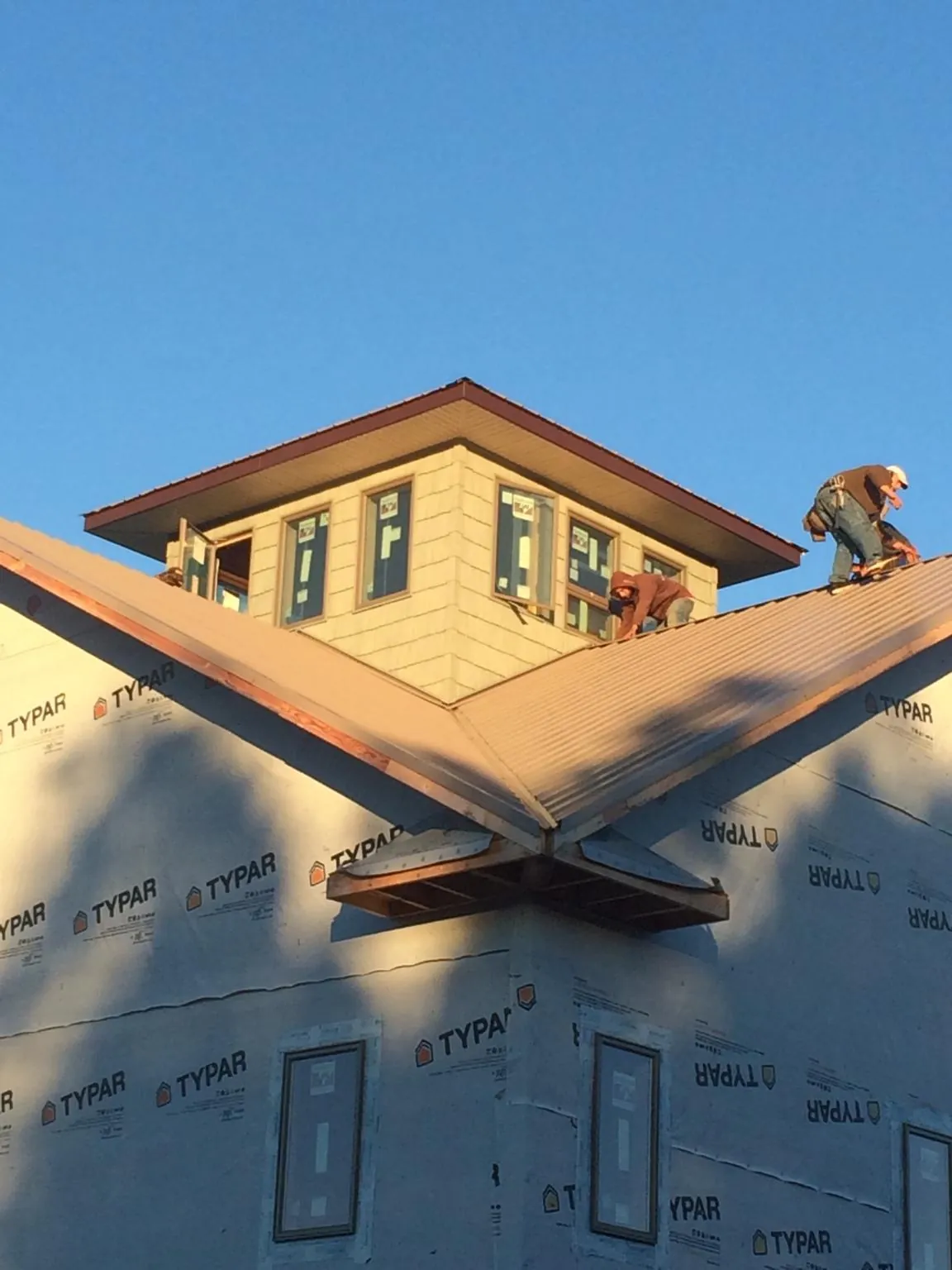 Roofers working around a rooftop cupola on a new metal roof at sunset — Roof Waterproofing in Harcourt by Roofing Brothers